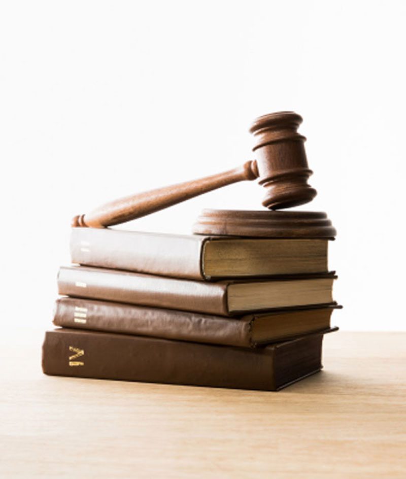 A wooden gavel resting on a stack of legal books on a desk.